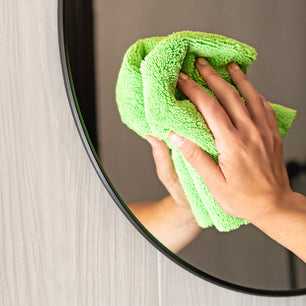 green microfiber cloth cleaning a mirror