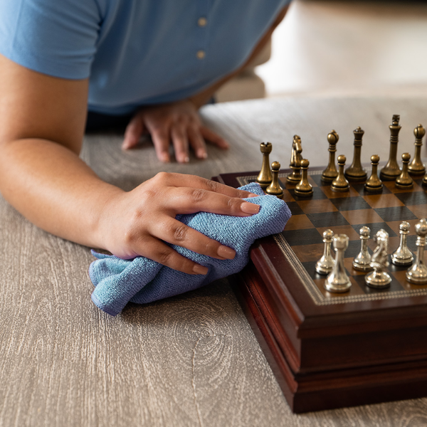 dusting a chess board with a blue microfiber cloth