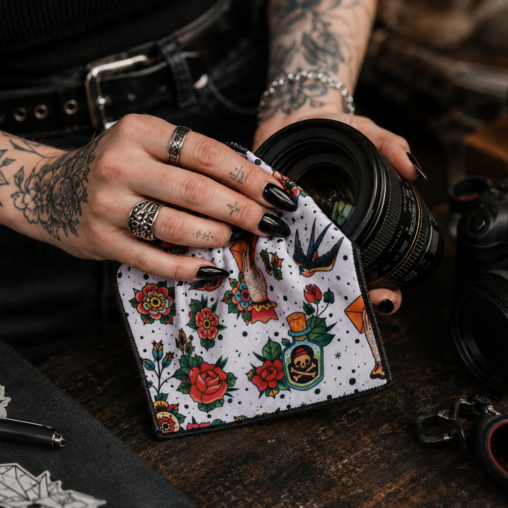 An alternative woman who is a photographer who has some tattoos and black coffin nails and she's polishing a DSLR camera lens