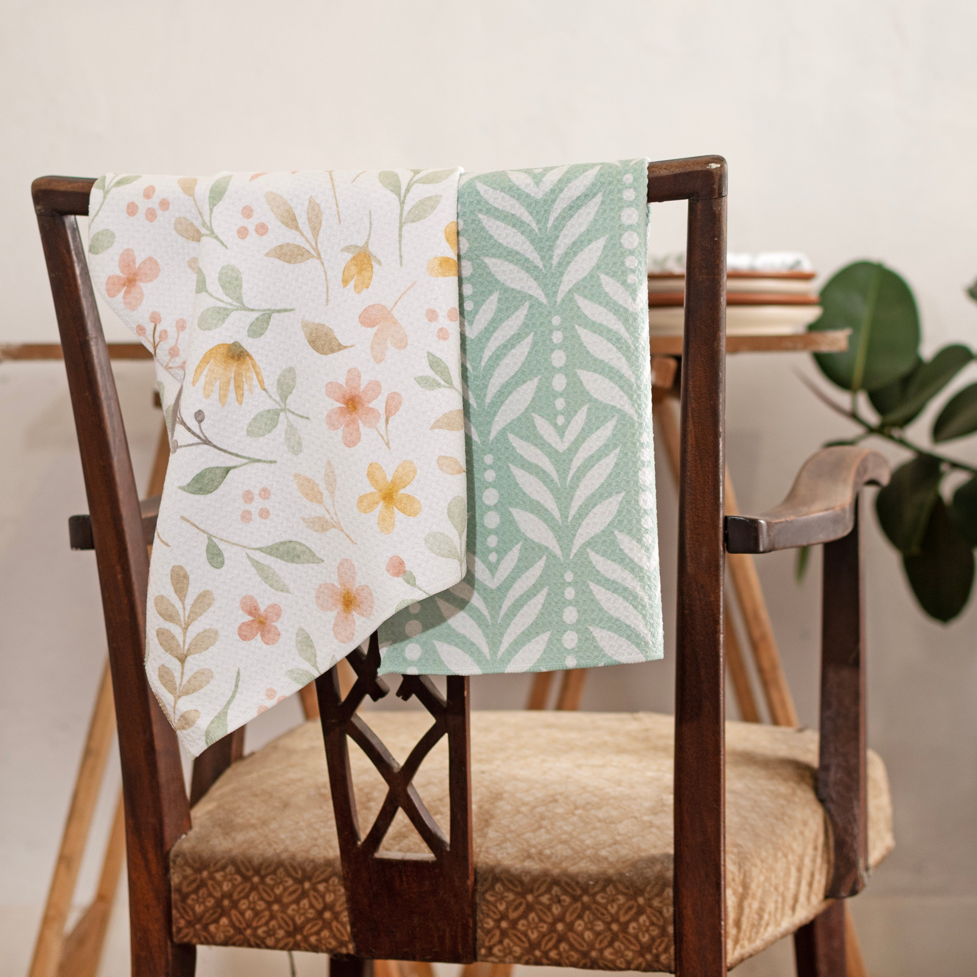 two custom printed microfiber waffle weave kitchen towels draped over a wooden chair back