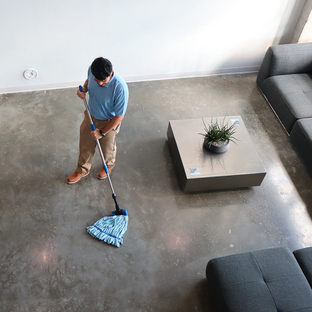 man mopping concrete with a blue microfiber tube mop