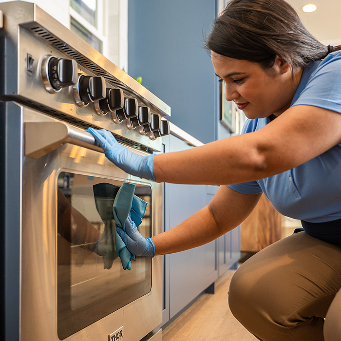 cleaning lady wiping an oven glass door with a microfiber cloth