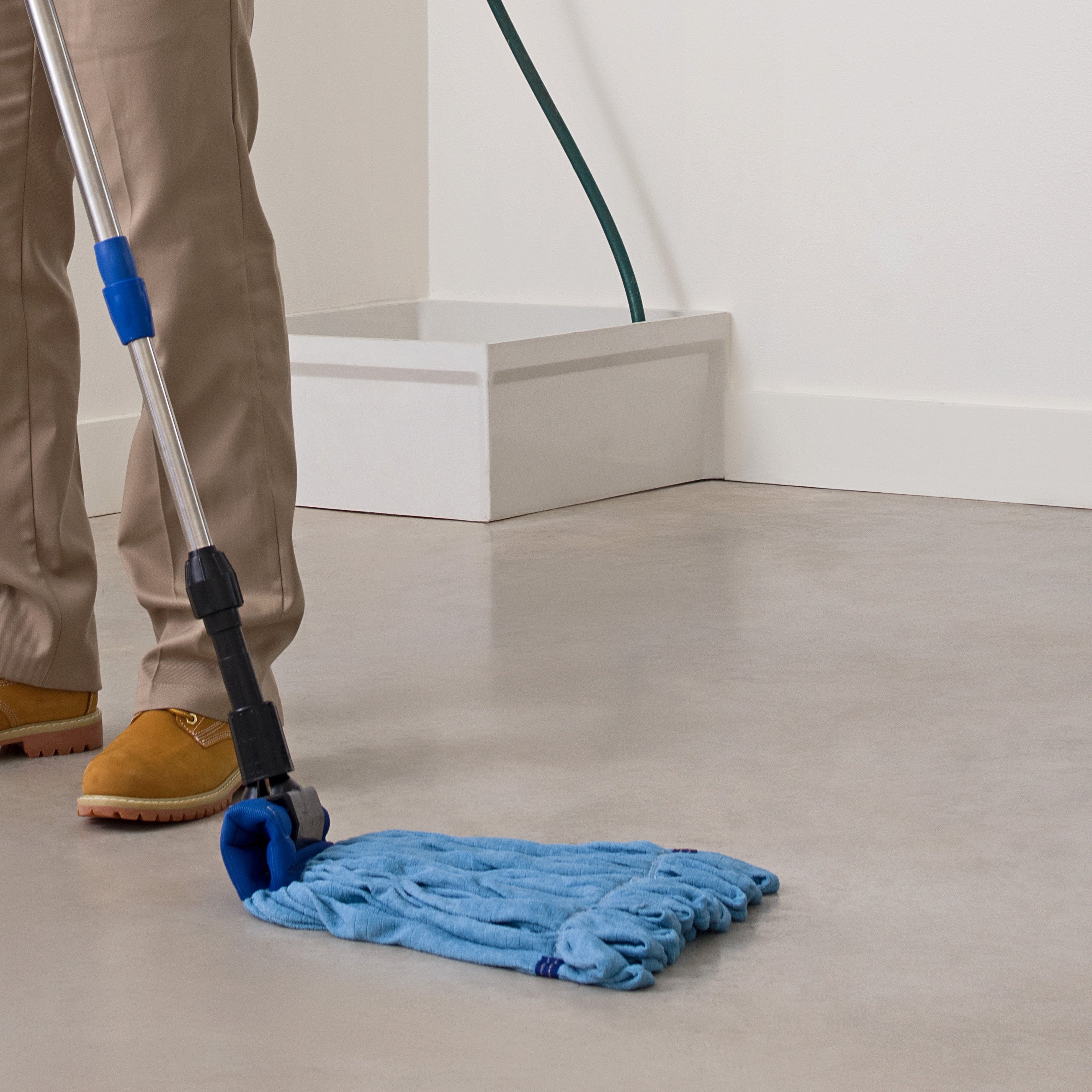 man mopping concrete with a blue microfiber tube mop