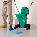 man mopping concrete with a blue microfiber tube mop and green bucket
