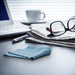 lens cloth, glasses, and newspaper on a desk