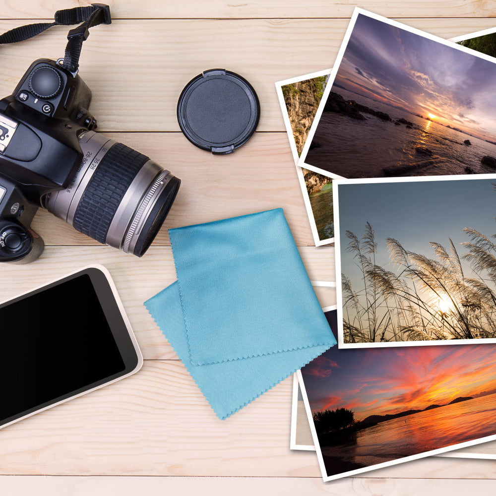 lens cloth, DSLR camera, iphone,  and photos on a tabletop