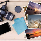 lens cloth, DSLR camera, iphone,  and photos on a tabletop