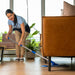  a woman mopping under a couch with a microfiber flat mop.